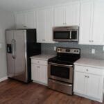 A Redwood Floor Kitchen With White Cabinets