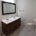 A Rectangular Bordered Mirror and Toilet Seat in the Bath