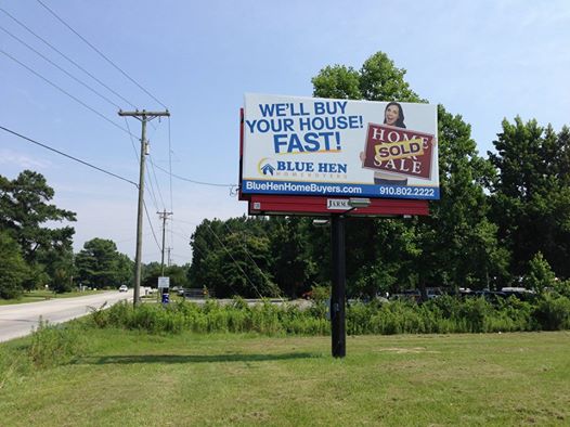 Advertisement of Blue Hen Homebuyers with a Billboard on a Pole