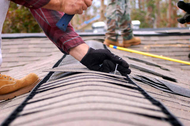 A Person Fitting a Screw in the Roof of a House