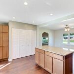 Illuminated Island Kitchen with Refrigerator and Storage Area