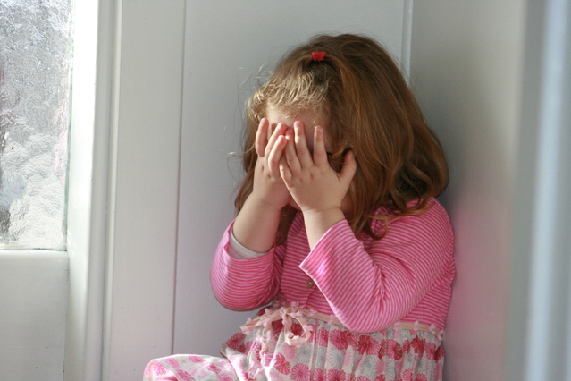 A Little Girl in Pink Dress Covering Her Face with both Hands