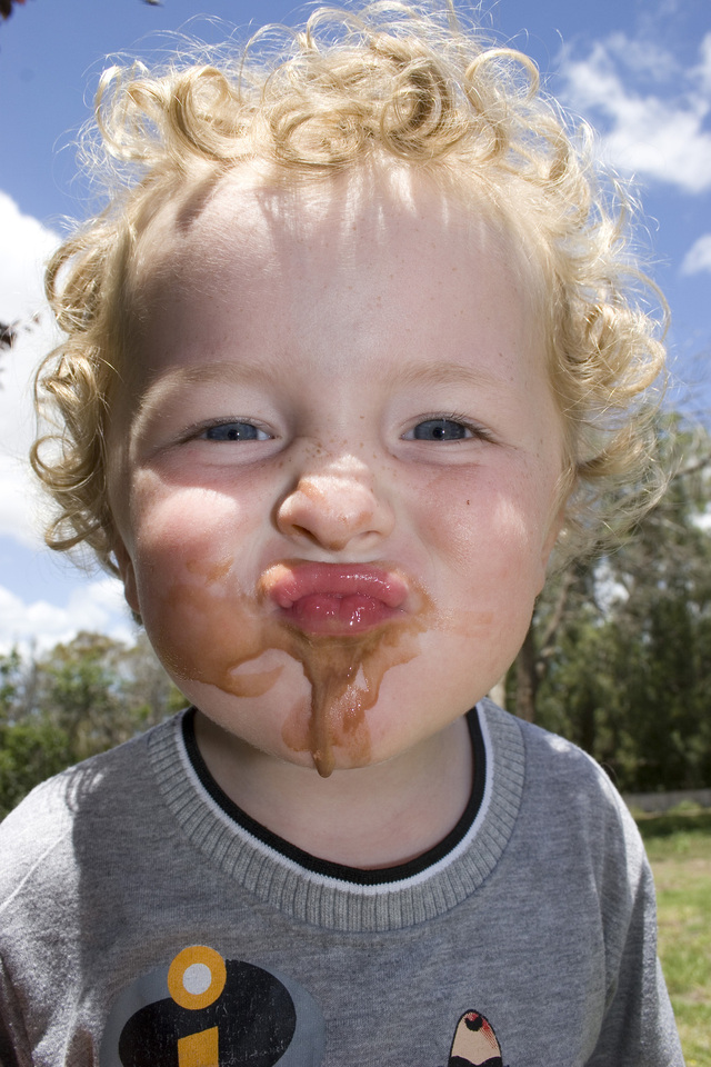 A Kid Standing with Icecream All Over Mouth and Face