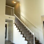 A Closed Gate Under Stairs with Railing with Lights Above