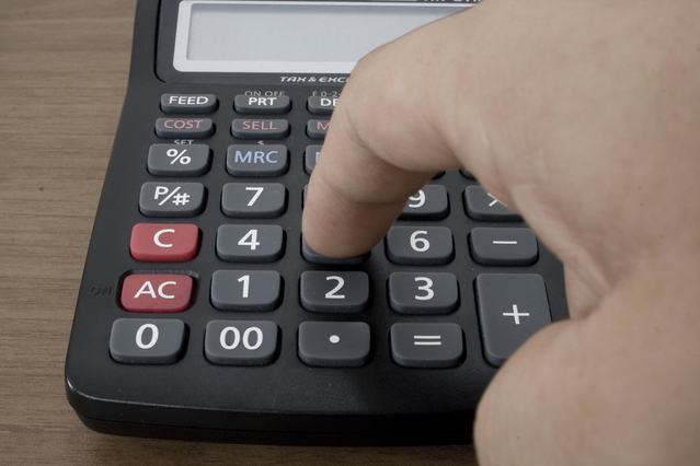 A Person Working on a Calculator, Finger on a Number