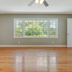 An Empty Room With Wooden Flooring And Large Window