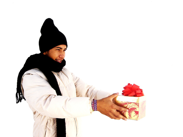 A Person in Winter Garments Holding A Gift with Red Ribbon