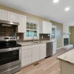 Kitchen with Granite Counter Tops, White Cabinets, and Appliances