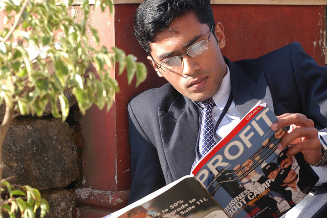 A Man in Suit Reading A Magazine with Full Concentration