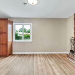 An Empty Wall with A Window, Covered Firepit, and Refrigerator in the House